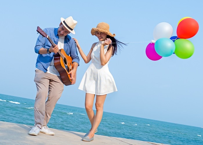 woman with baloons and man playing guitar